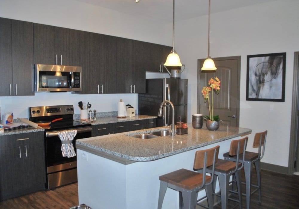 Apartment kitchen with hanging lighting and dark wood cabinets at Addison at Tampa Oaks in Temple Terrace, Florida