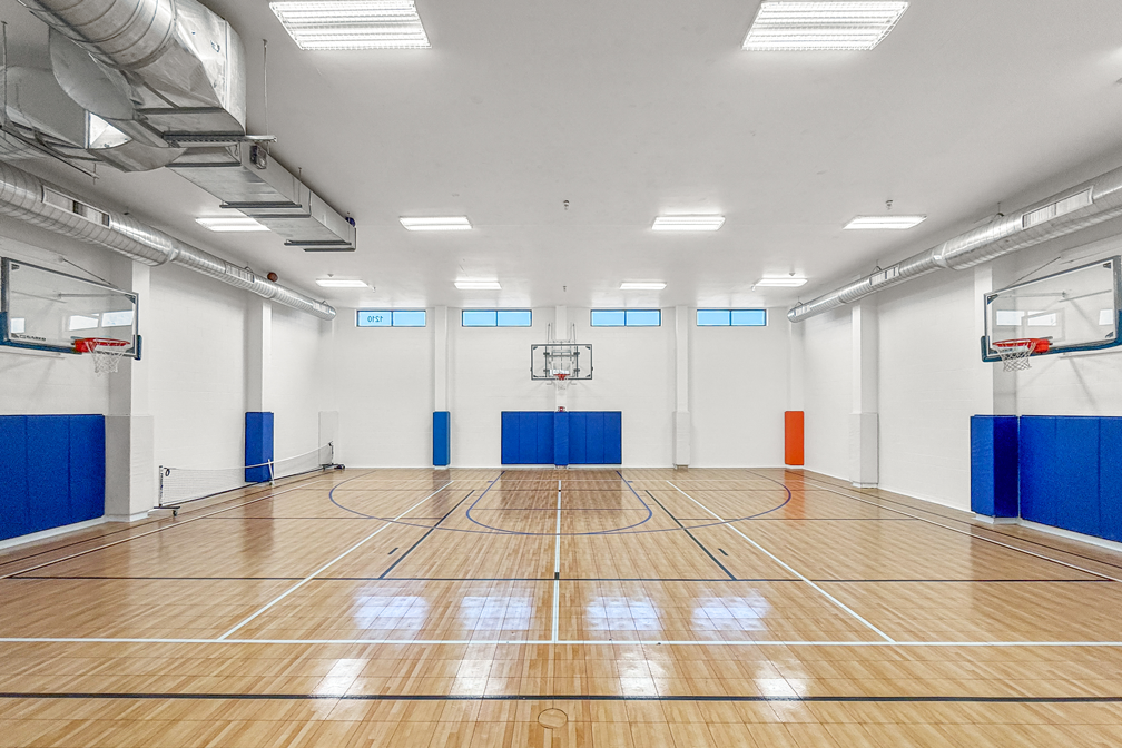 Indoor basketball court with hardwood flooring and dual hoops at The Franklin in Ankeny, Iowa
