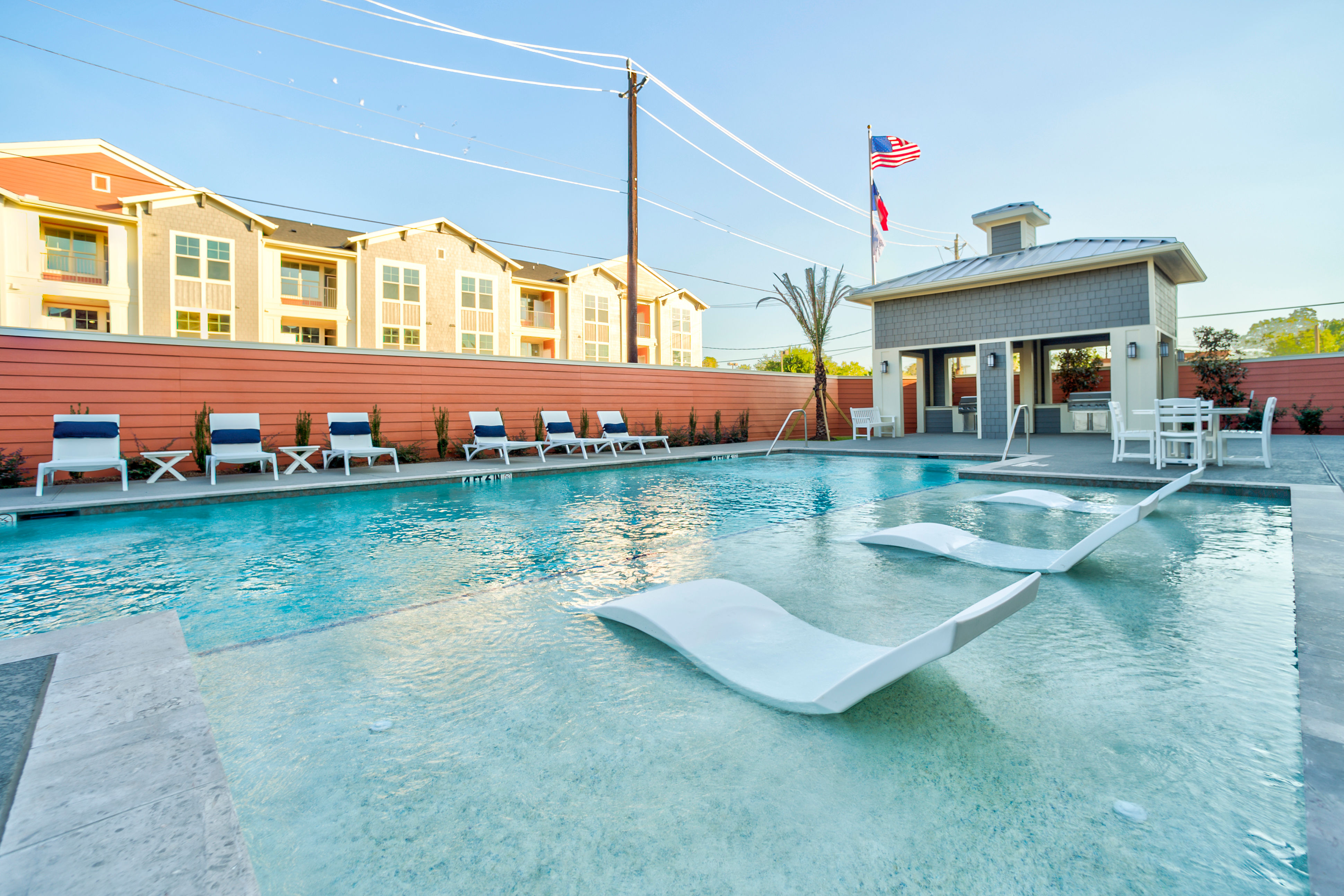 Couple relaxing on floats in sparkling blue pool under bright sun at Magnolia Park Apartments in Houston, Texas 
