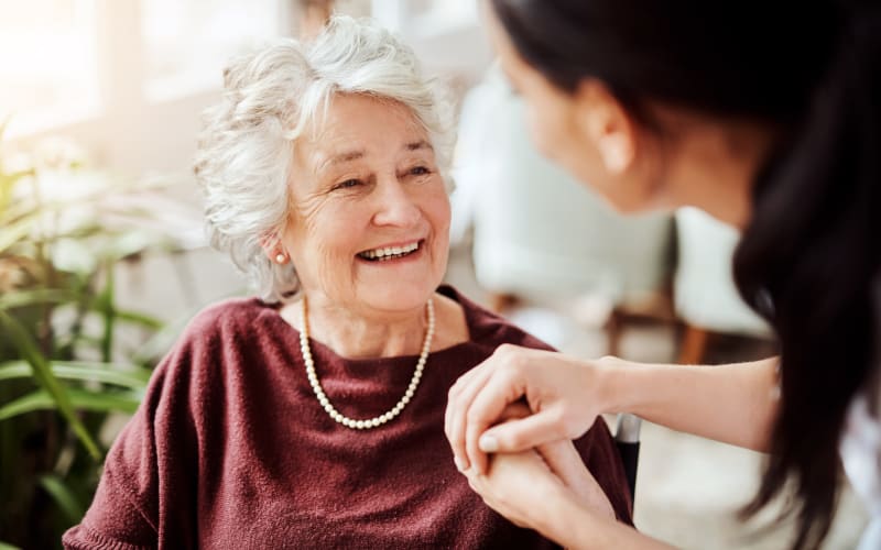 Resident smiling and holding hands with a caretaker at a The Blake community