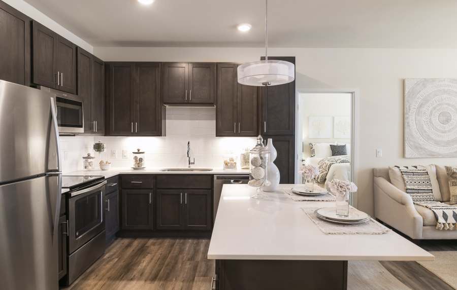 Kitchen with stylish hanging light with hardwood flooring at Altair At The Preserve in O'Fallon, Missouri