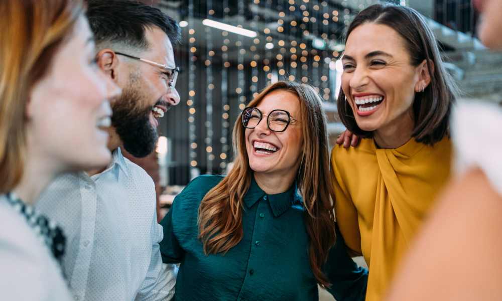 The resident is smiling and laughing with others.at ARTISAN Management Group in Des Moines, 