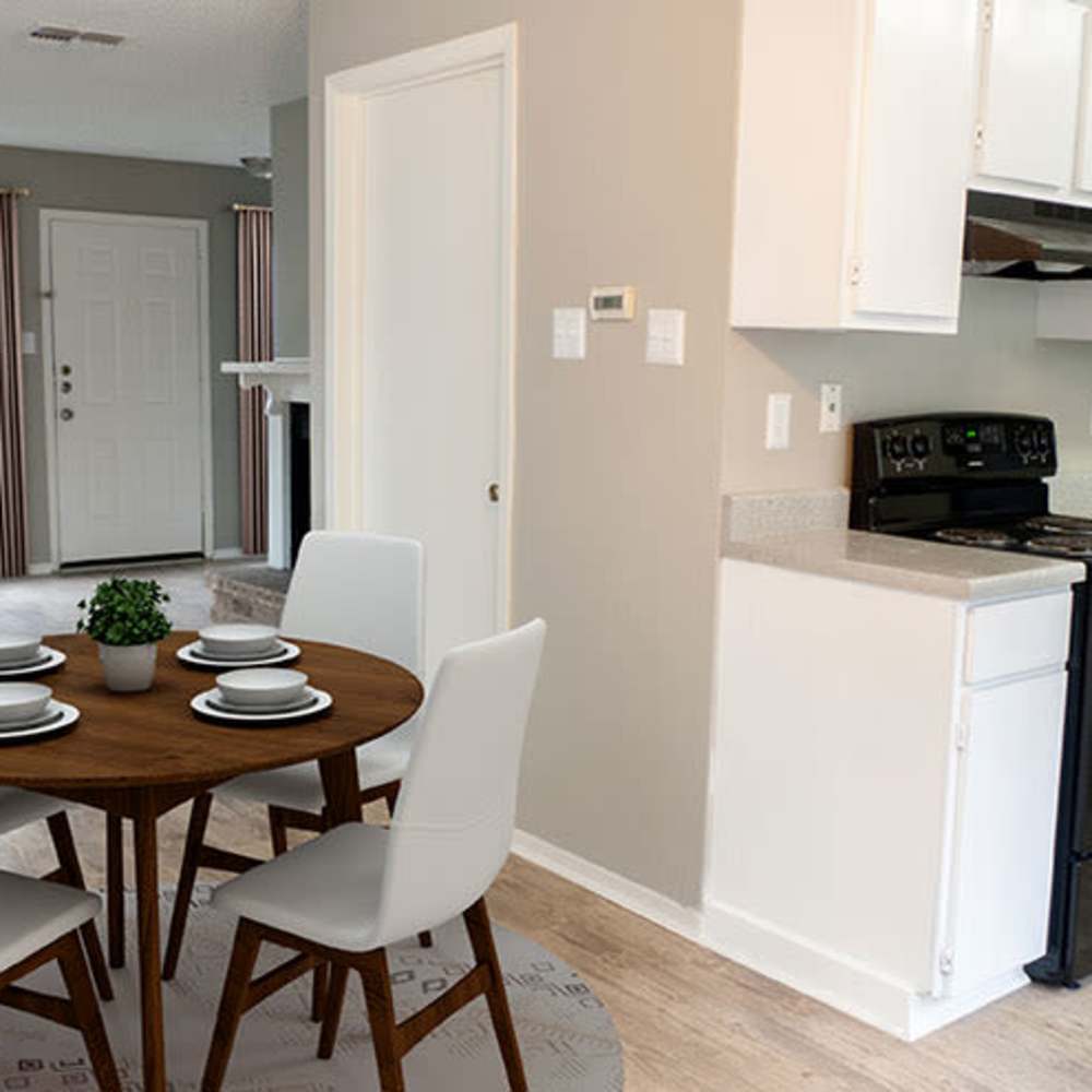 Round wooden dining table with white chairs at The Camaron Townhomes & Flats in San Antonio, Texas