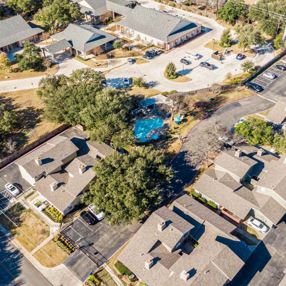 Swimming pool surrounded by trees and buildings at The Camaron Townhomes & Flats in San Antonio, Texas