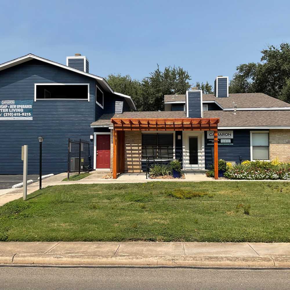 Blue and beige building with a wooden trellis at The Camaron Townhomes & Flats in San Antonio, Texas