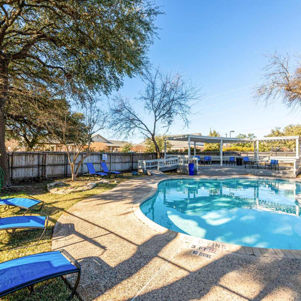 Chairs positioned around a swimming pool at The Camaron Townhomes & Flats in San Antonio, Texas