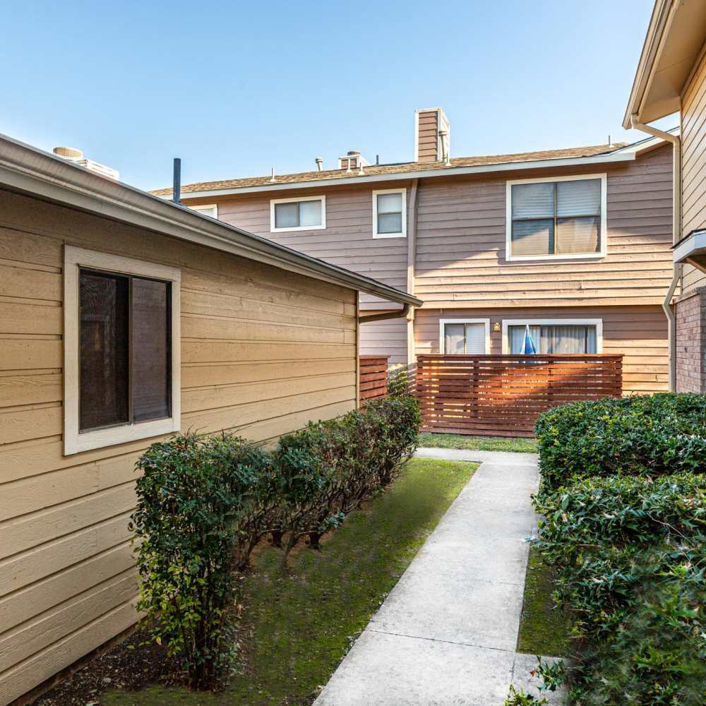 Pathway between buildings with shrubs at The Camaron Townhomes & Flats in San Antonio, Texas