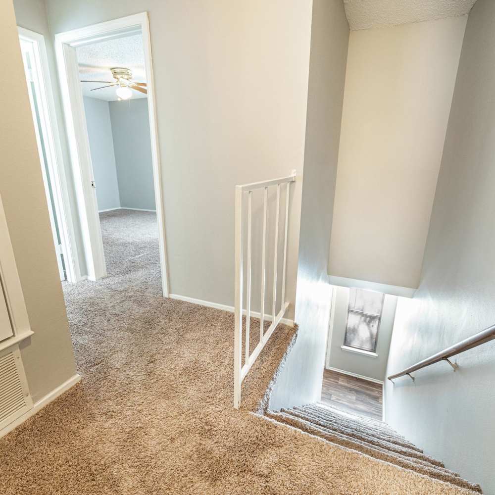 Stairs leading down with carpeted hallway at The Camaron Townhomes & Flats in San Antonio, Texas