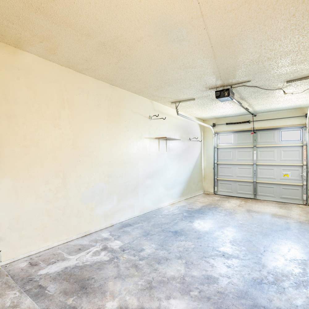 Empty garage with concrete floor and wall shelves at The Camaron Townhomes & Flats in San Antonio, Texas