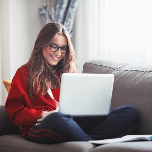 Woman smiling while working on laptop at Bayview Student Living in North Miami, Florida