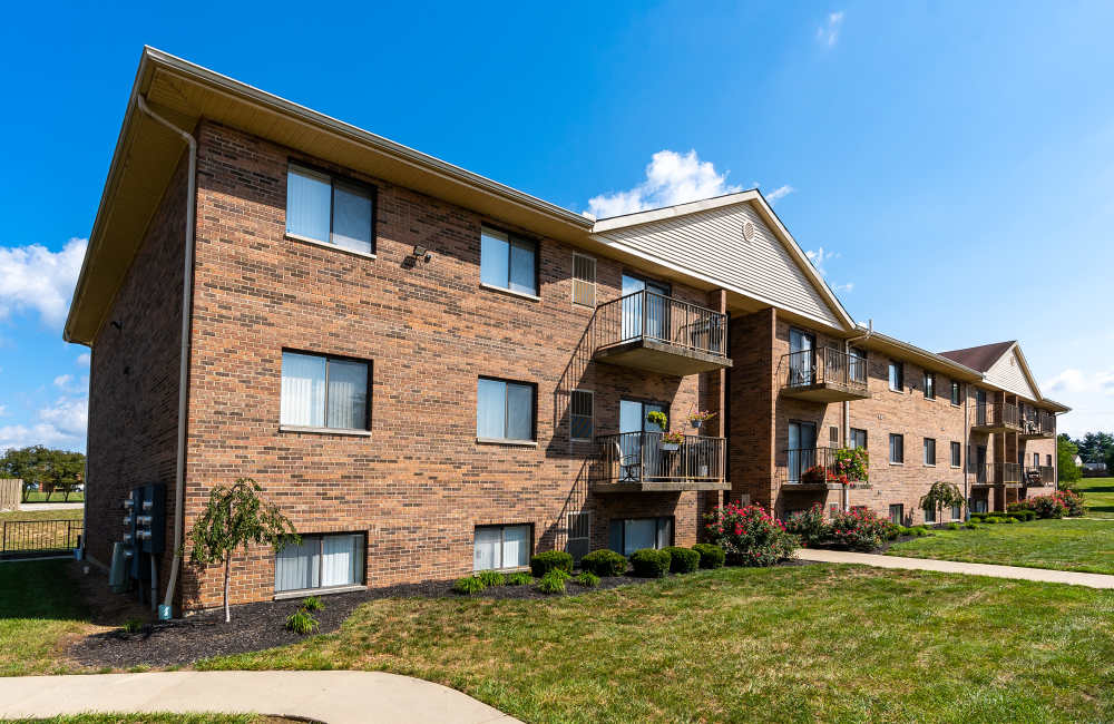 Brick building with balconies and landscaping at Indian Footprints Apartments in Harrison, Ohio