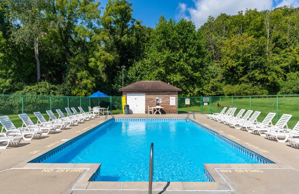 Green trees in background with pool area at Indian Footprints Apartments in Harrison, Ohio