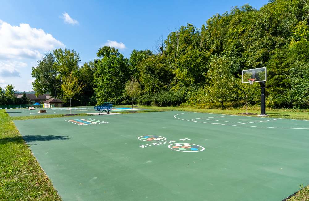 Basketball hoop with court and trees at Indian Footprints Apartments in Harrison, Ohio