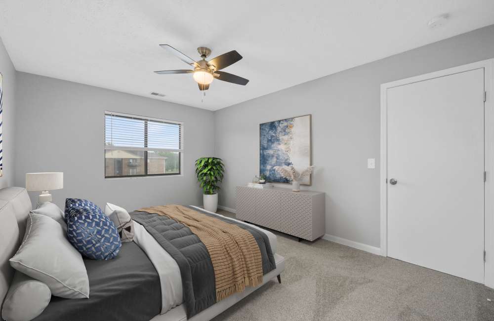 Bed with decorative pillows and blanket at Indian Footprints Apartments in Harrison, Ohio