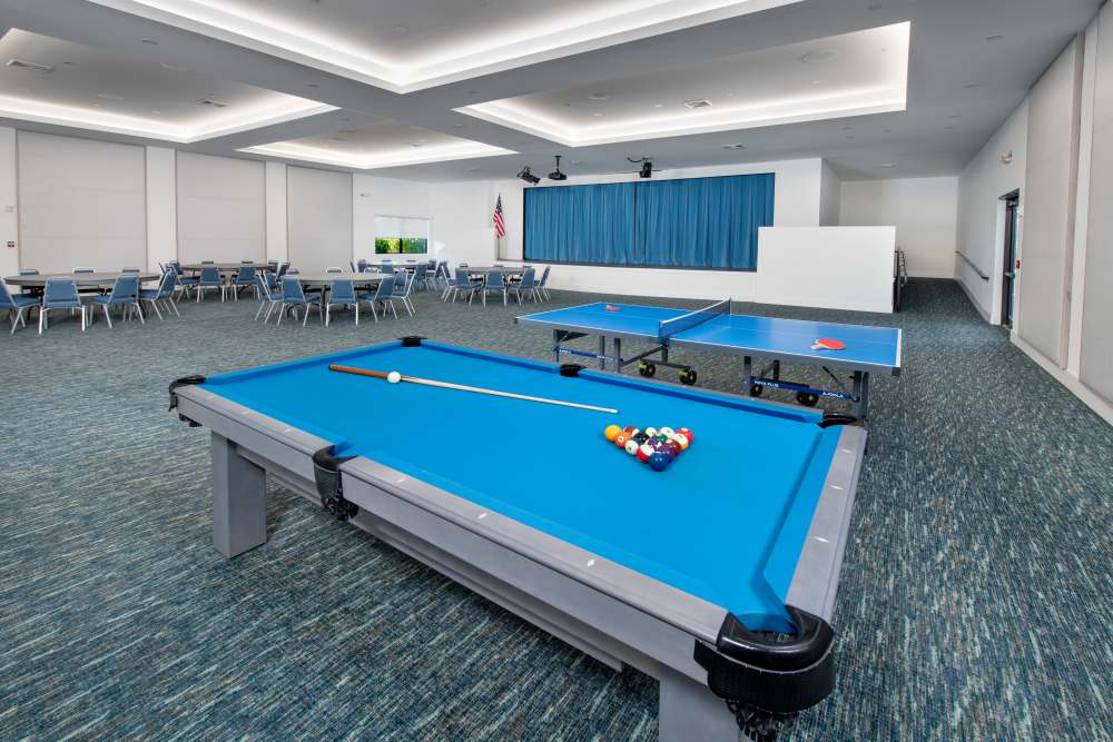 Game room featuring a blue pool table and ping pong tables with seating areas in background at Solera at Avalon Trails in Delray Beach, Florida