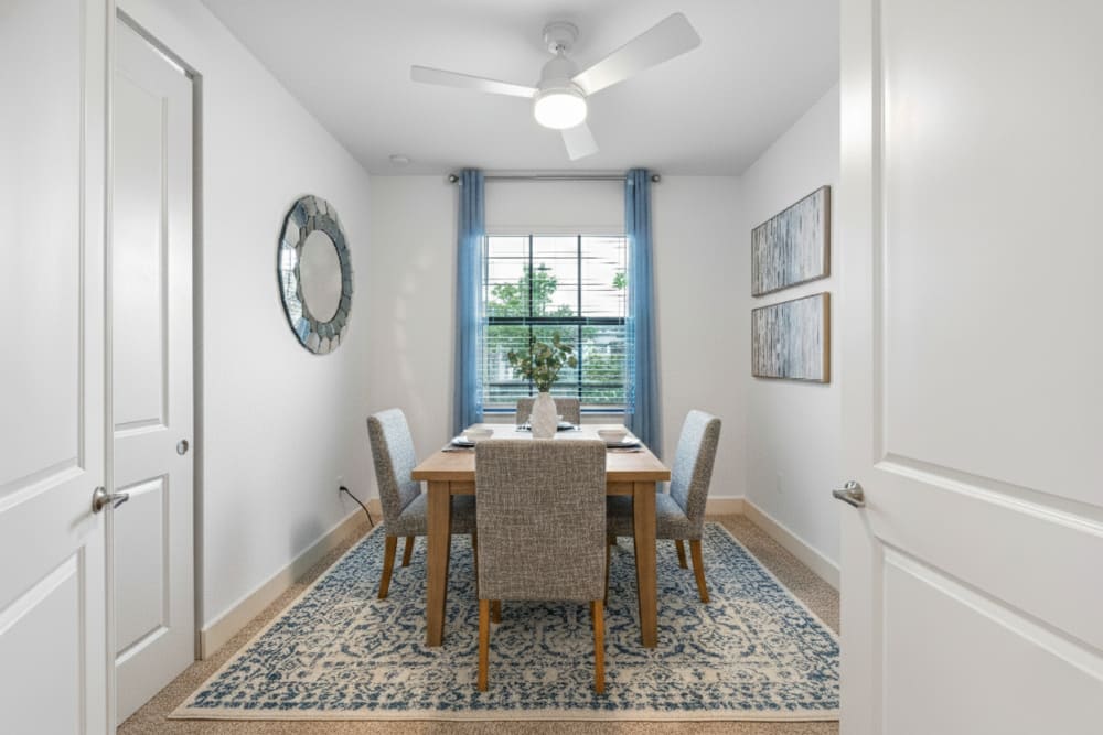 Bright dining area with a wooden table, four chairs, and decorative wall art at Solera at Avalon Trails in Delray Beach, Florida