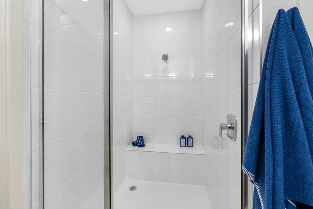 Modern walk-in shower with glass door and blue towel hanging on the wall at Solera at Avalon Trails in Delray Beach, Florida