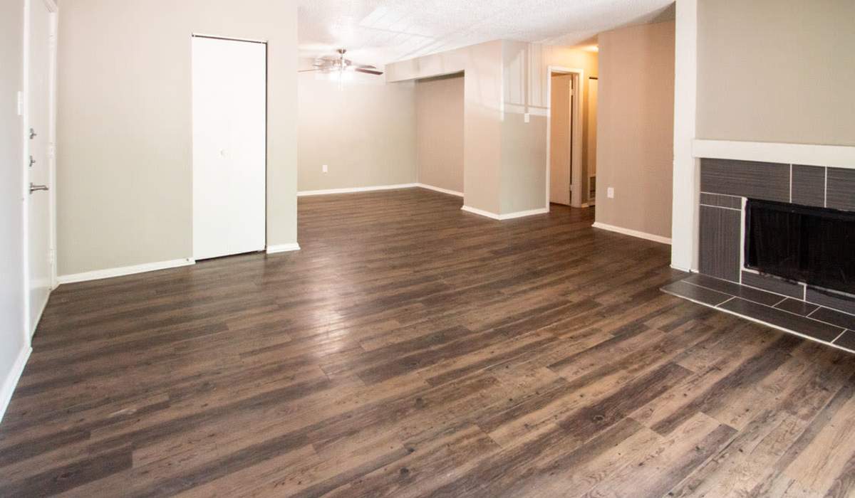 Open layout living area with wood-style flooring and decorative fireplace, inviting natural light at Riatta Ranch Apartments in Abilene, Texas