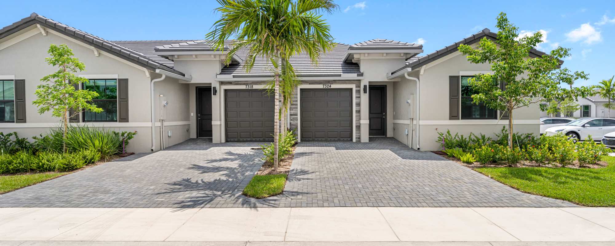 Two garages with paver driveway and landscaping at Solera at Avalon Trails in Delray Beach, Florida