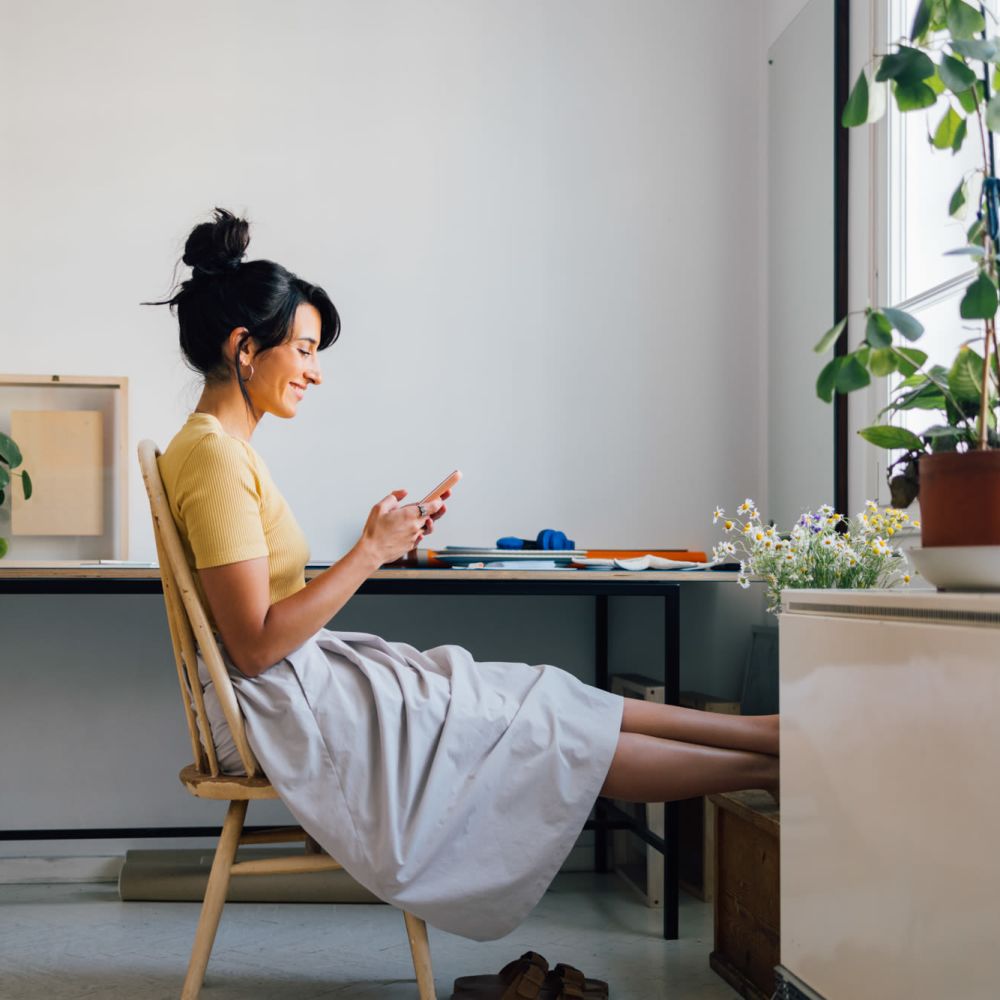 Woman relaxing and using phone in bright space at Serenity at Cityside in Houston, Texas