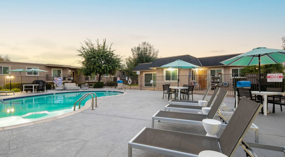 Resort-style pool with lounge chairs and umbrellas at Wexford Manor Apartments in San Diego, California