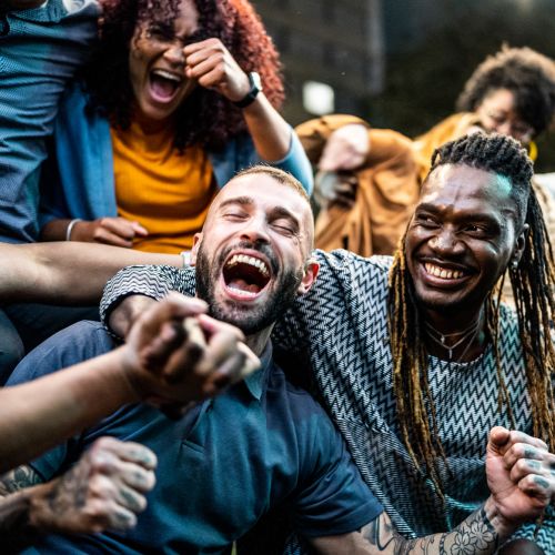 Group of friends laughing and celebrating together in a lively atmosphere at Jordache Park Apartments in Spencerport, New York