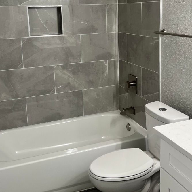 Modern bathtub with sleek tile walls at Serenity at Cityside in Houston, Texas