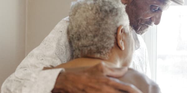 Resident and a staff member shoulder-to-shoulder looking out a window at a WISH community