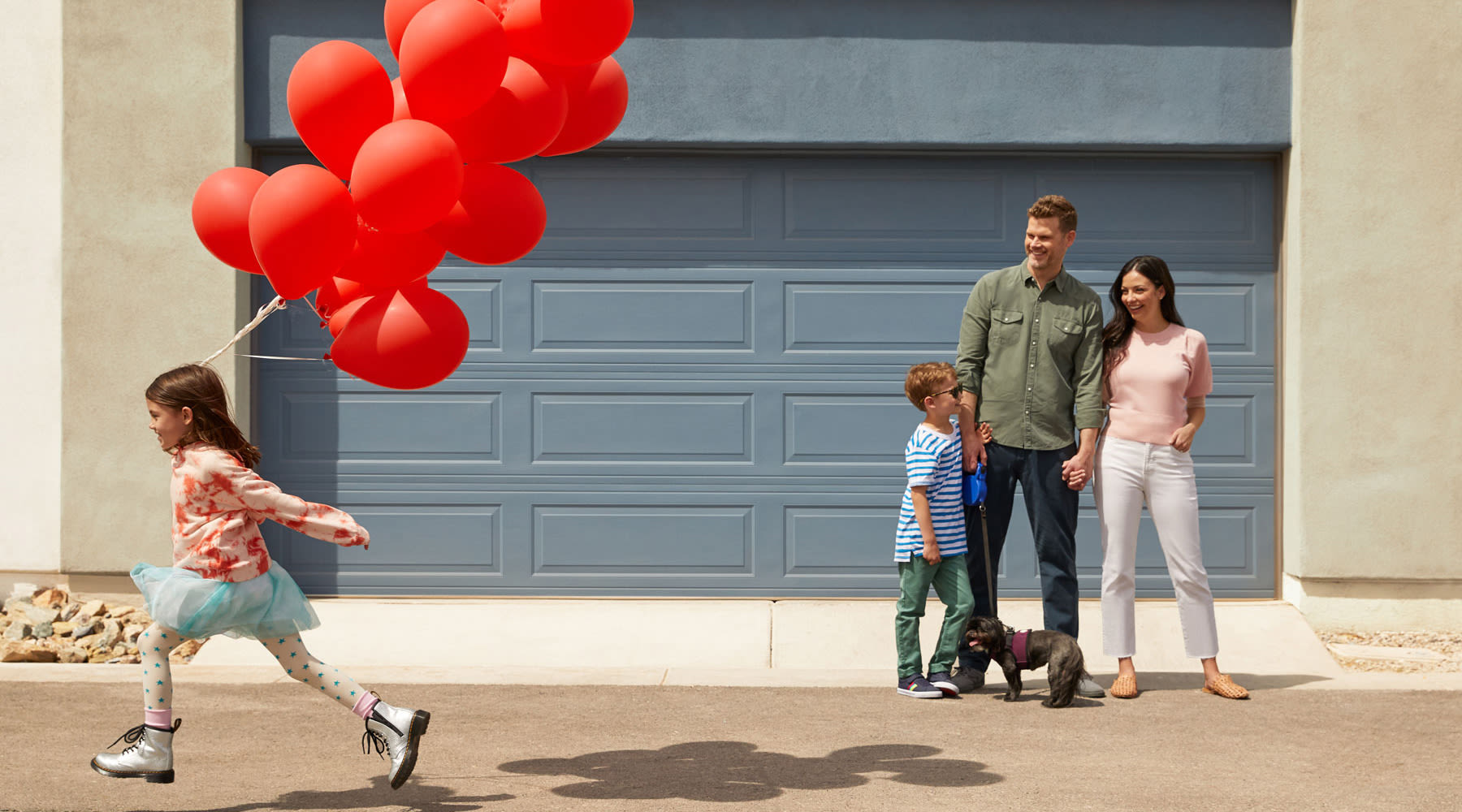 Girl running away from her family with her red balloons in front of a garage at BB Living in Scottsdale, Arizona