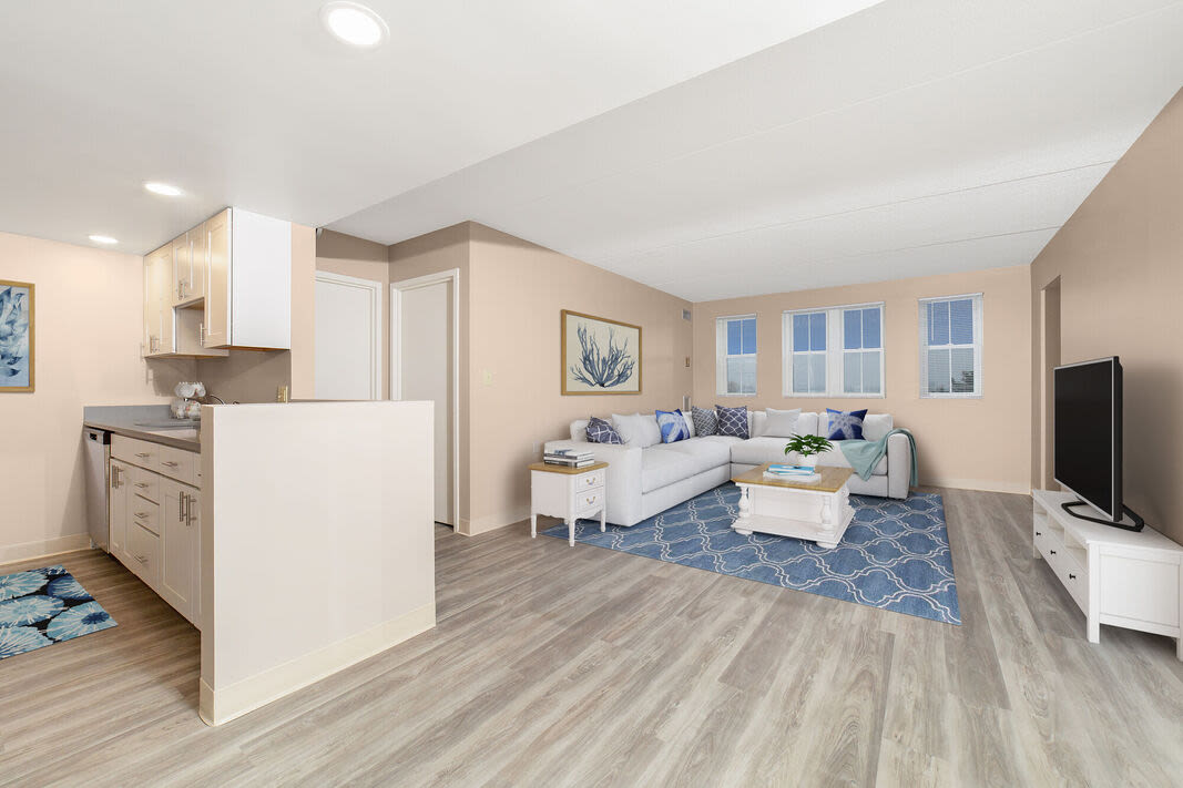 View of the living room with a comfortable couch, hardwood flooring and an open kitchen at Anchors Weigh in Chelsea, Massachusetts