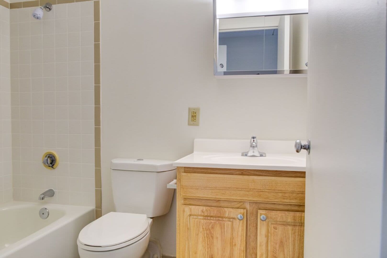 Bathroom with a toilet, wooden storage units and a large mirror at Anchors Weigh in Chelsea, Massachusetts