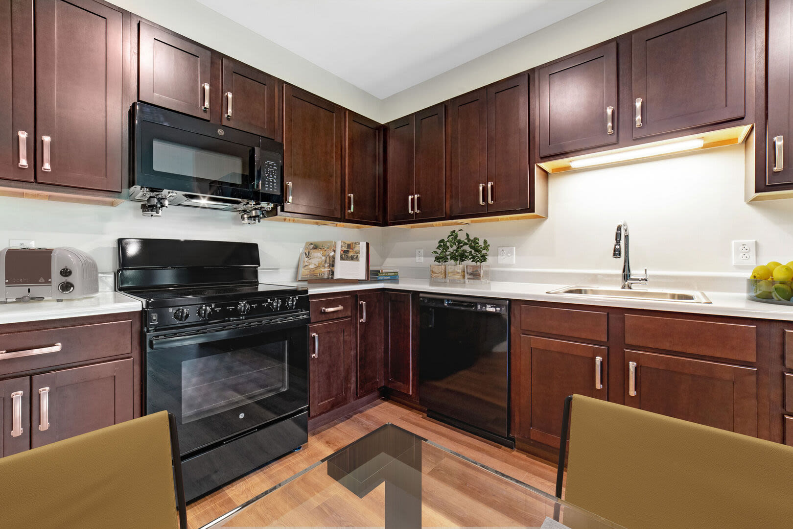 Fully equipped kitchen with granite countertops stainless steel appliances like a dish washer, stove, and drawer microwave at Solara in Tiverton, Rhode Island
