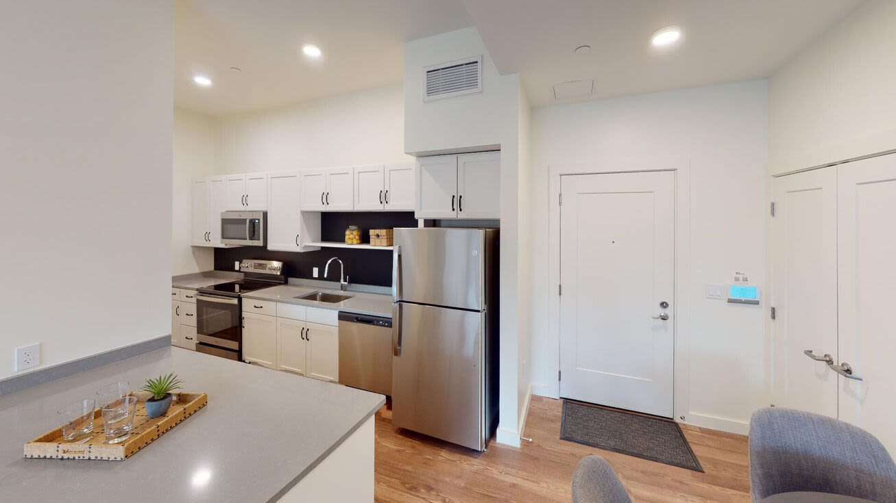 Kitchen with trendy appliances including refrigerator, dish washer and white cabinetry at The Mcelwain School Apartments in Bridgewater,Massachusetts