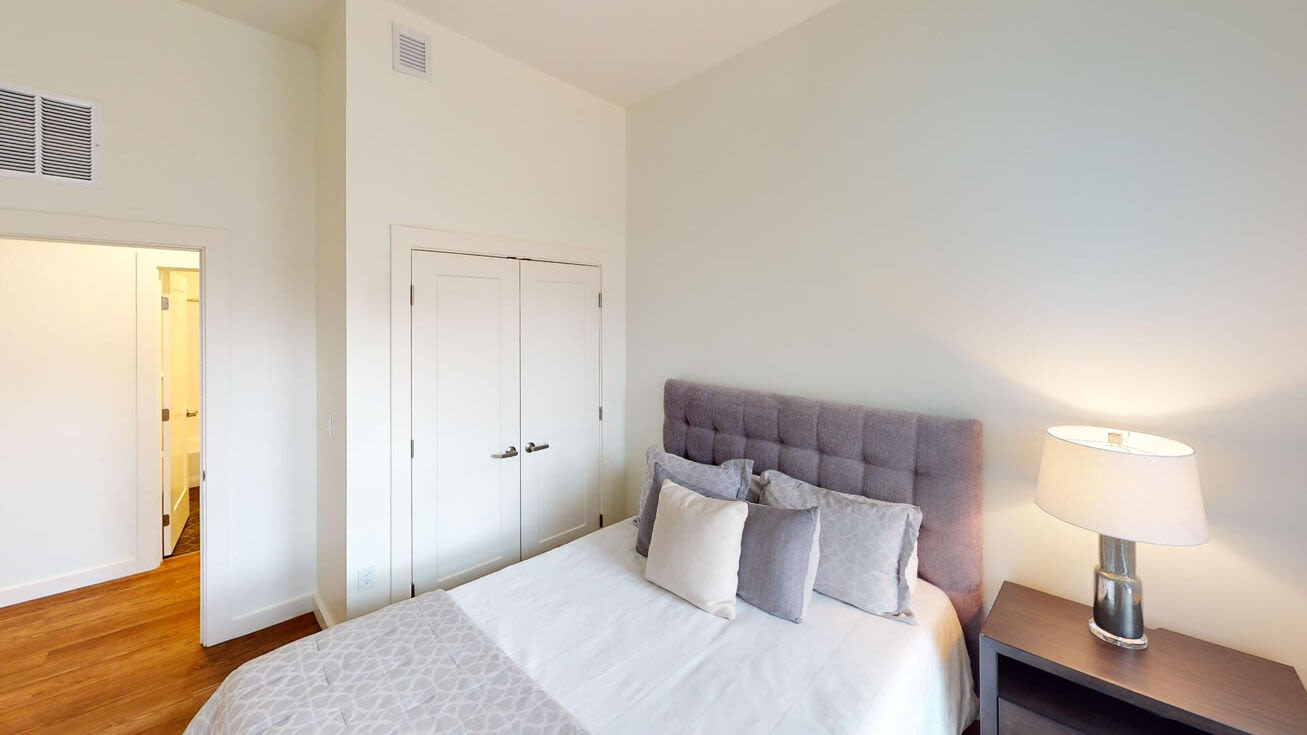 Bright bedroom with bed and closet space at The Mcelwain School Apartments in Bridgewater,Massachusetts