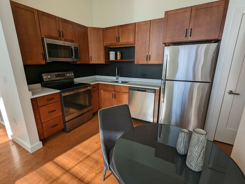 Fully equipped kitchen with granite countertops stainless steel appliances like a refrigerator, stove, and drawer microwave at The Mcelwain School Apartments in Bridgewater,Massachusetts