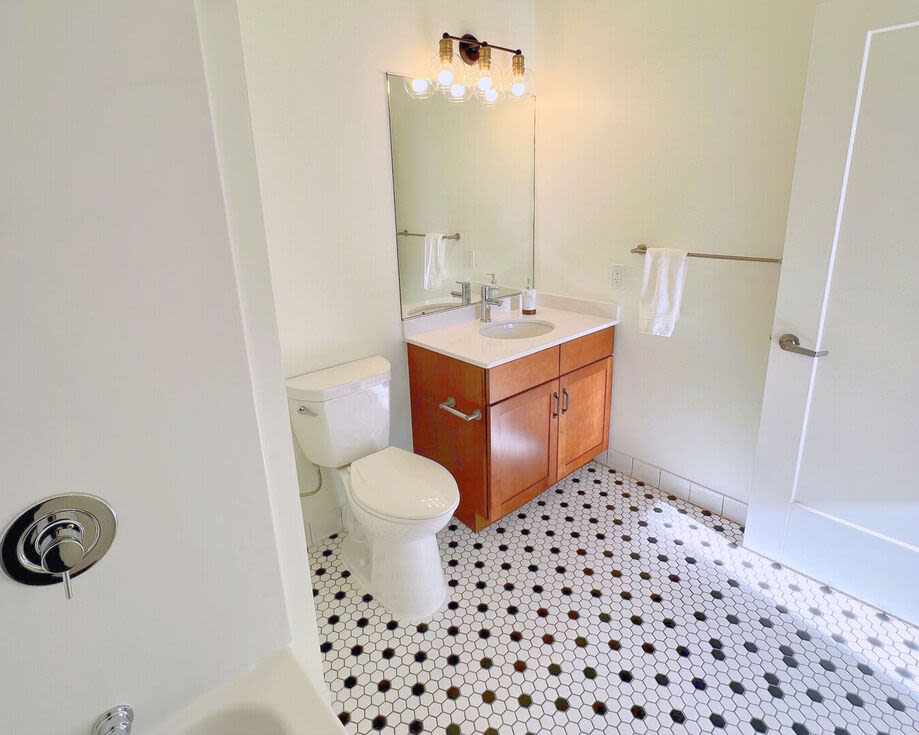 Bright bathroom with mirror, sink and storage space at The Mcelwain School Apartments in Bridgewater,Massachusetts