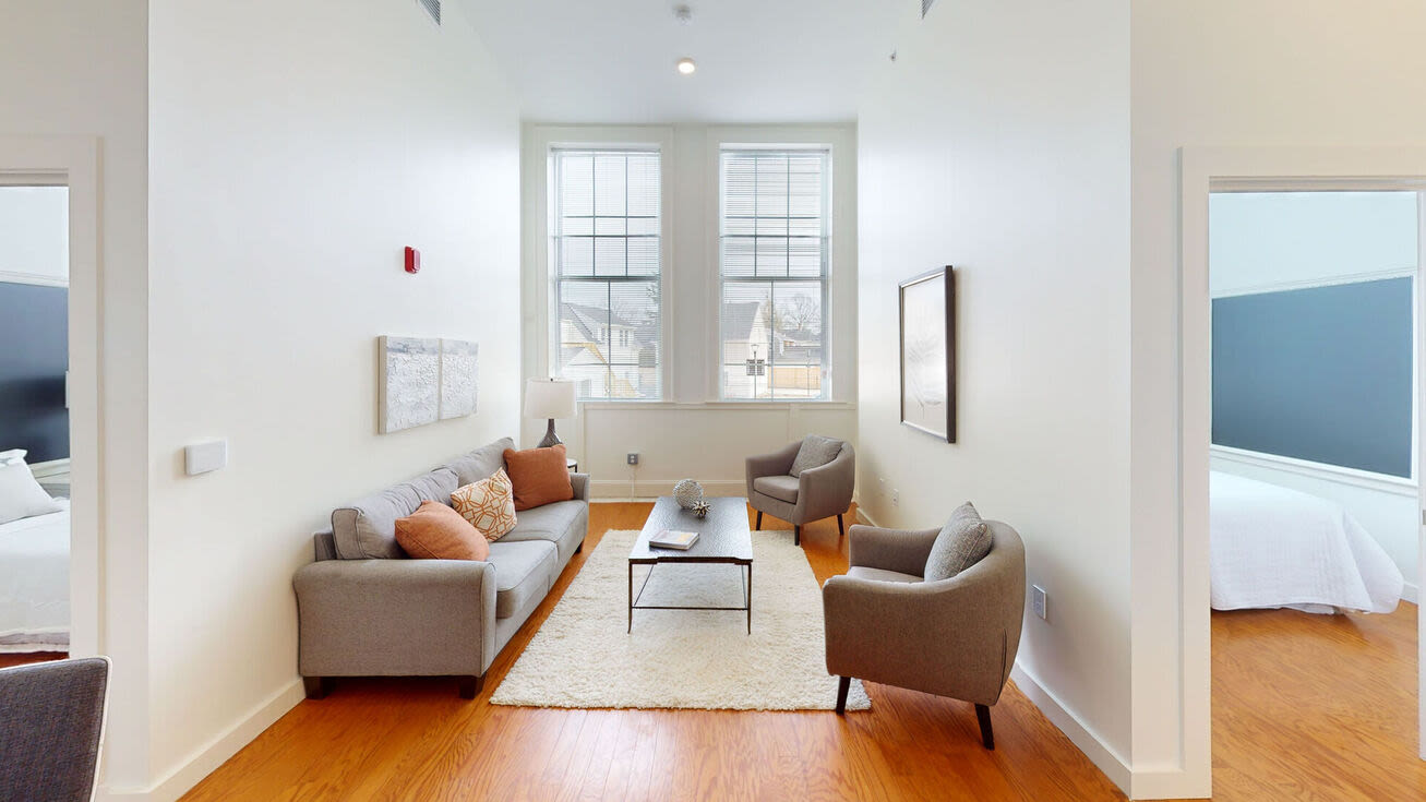 Spacious living room couch, chairs and windows at The Mcelwain School Apartments in Bridgewater,Massachusetts