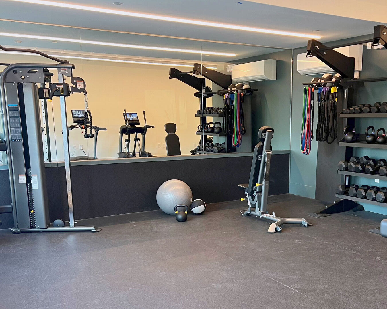 Fully-equipped gym with treadmills, weight machines, and mirrors at The Mcelwain School Apartments in Bridgewater,Massachusetts