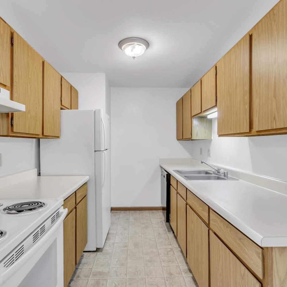 Cozy kitchen with white granite countertop and brown cabinetry at Prairie Apartments in Salem,Wisconsin