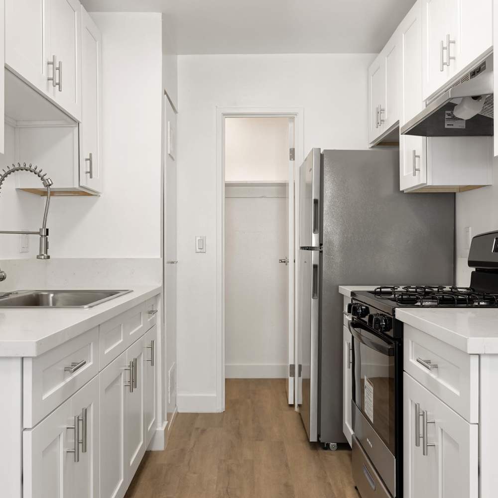 Modern kitchen with white cabinets, stainless steel appliances, gas stove, and wood flooring at Valle at Mission in Escondido, California