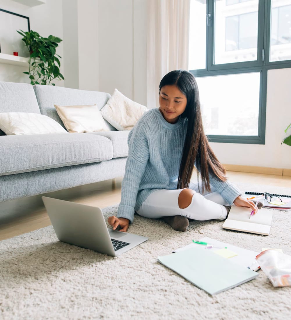 Student studying in her bright living room at The Holly in Lubbock, Texas