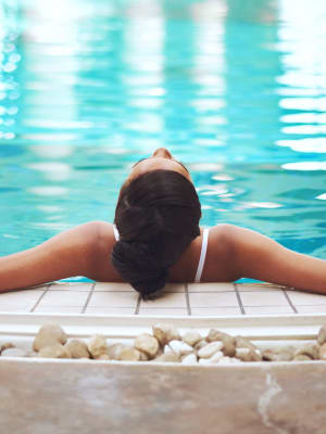 Resident sitting on the side of the pool soaking their legs at The Wright Apartments in Centennial, Colorado