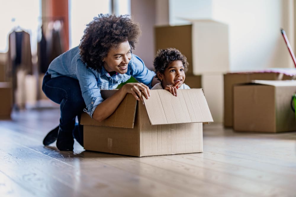 A parent and child play with a cardboard box while unpacking at Our Self Storage.