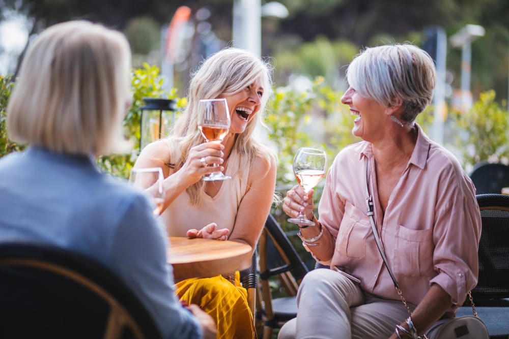 Residents sitting outside at table laughing at Atlas Point at Prestonwood in Carrollton, Texas.