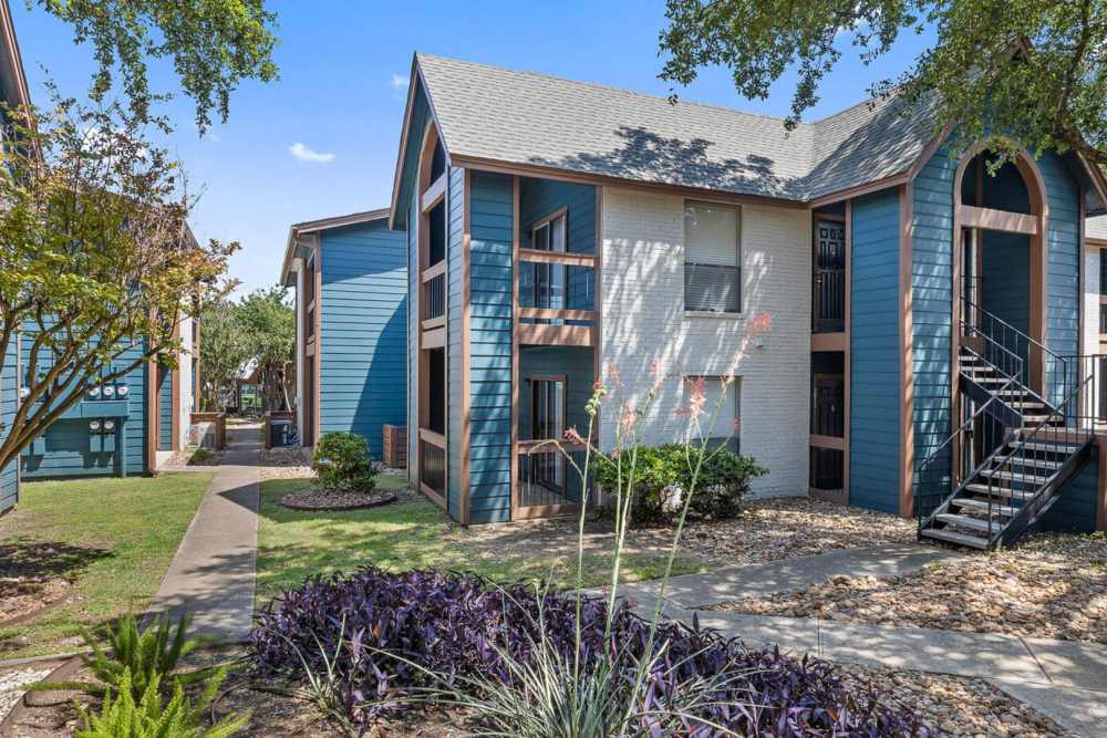 View of the apartment building, concrete pathway and staircase leading to the main door at Hill At Woodway in San Antonio, Texas