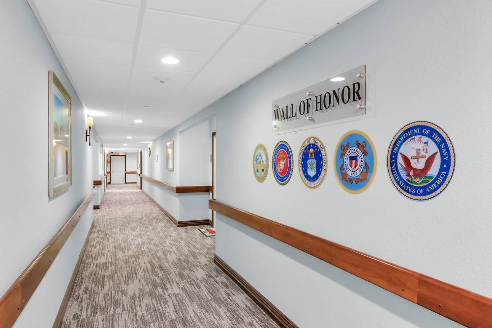 A hallway featuring two signs mounted on the wall at Villas of Holly Brook Shelbyville, Shelbyville, Illinois