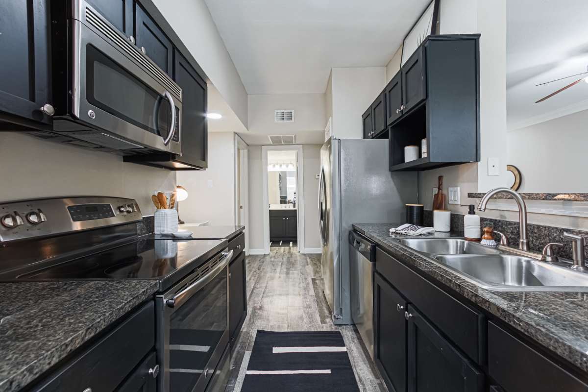Kitchen with dark walnut color cabinets at The Village At Bellaire Apartments in Houston, Texas