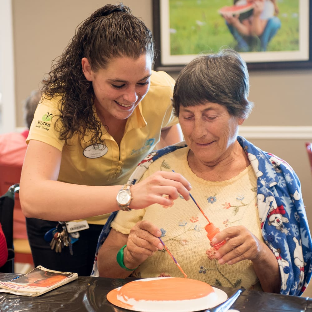 Staff member helping a resident with an art project at Inspired Living.