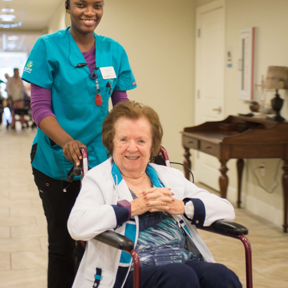 Staff member helping a resident in a wheelchair at Inspired Living Lewisville in Lewisville, Texas. 