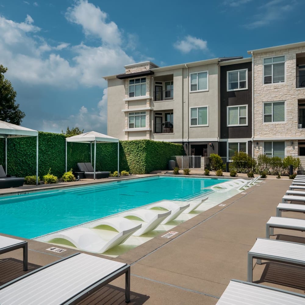 Swimming pool surrounded by chaise lounge chairs on a beautiful day at Lakeshore Pearl in Austin, Texas